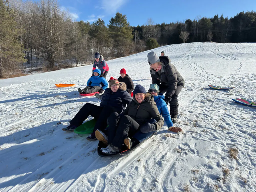 Participants and friends sledding down a snowy hill together
