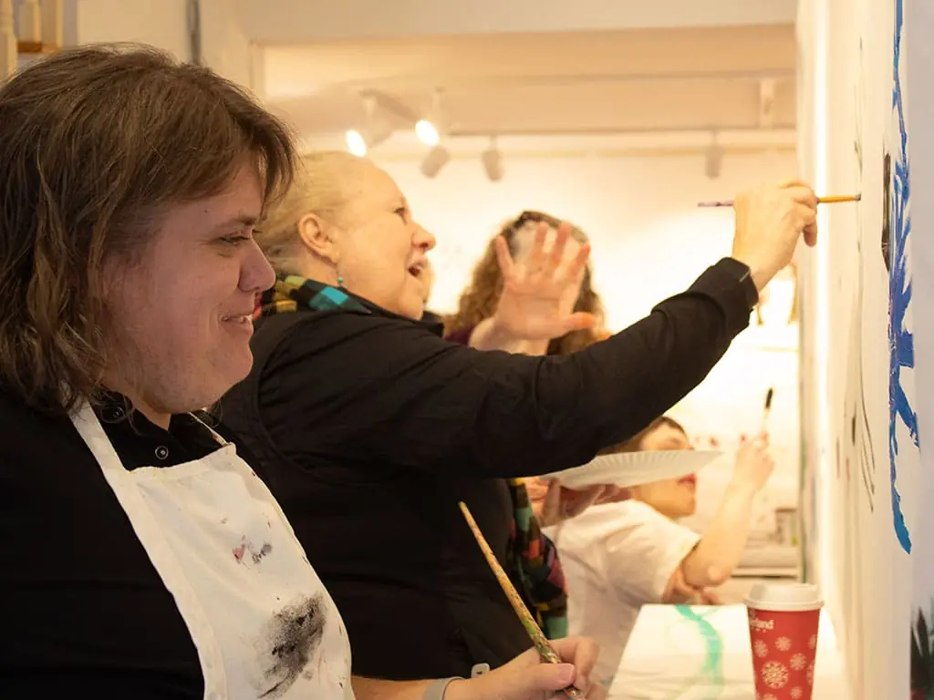 Participants in art aprons painting a mural together