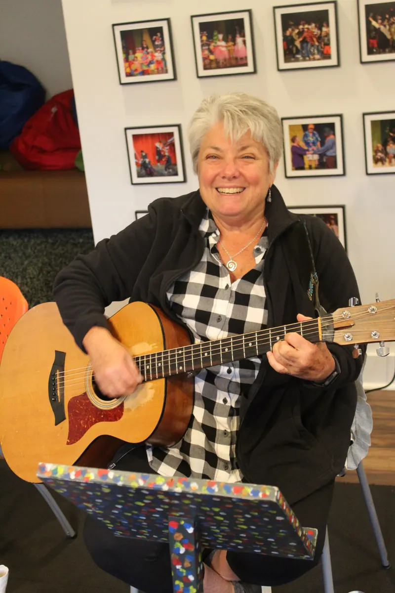 Kerry Rosenthal smiling as she plays her guitar